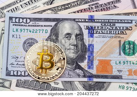 Golden yellow bitcoin on hundred banknotes background. High resolution photo.