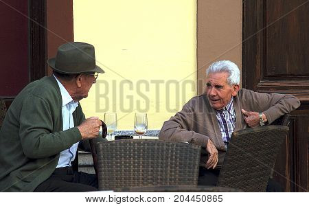 Ronda, Spain - May 3, 2014: Elderly men talking in the street cafe in Ronda, Spain