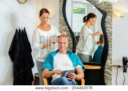 Female Hairdresser Cutting Hair Of Man