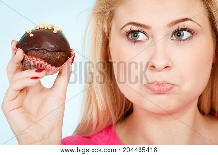 Diet sweets food concept. Woman holding delicious chocolate cupcake with peanut frosting about to take bite