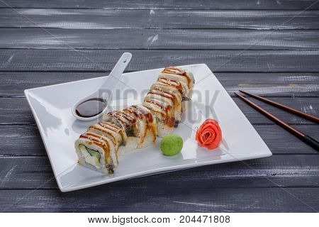 Kanada sushi rolls with salmon eel Philadelphia cheese avocado and cucumber served on white flat plate with chopsticks over blsck background. Asian menu for gourmets in luxury restaurant