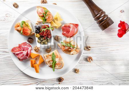 Selection of tasty bruschetta or canapes on taosted baguette and quark cheese topped with smoked salmon, shrimp, prawn, olives, tomato and chorizo sausage