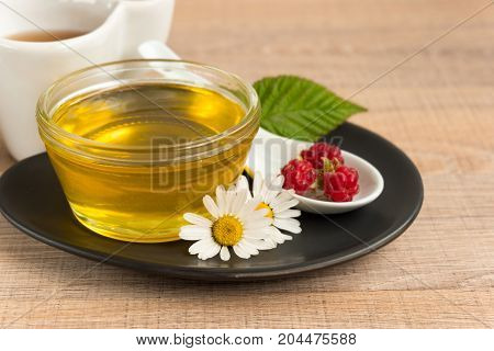 A Cup Of Honey On The Plate. The Honey In The Spoon Drops, Raspberry, Chamomile, Derevyanny Backgrou