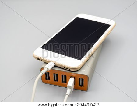Smart phone charging with multiport USB power adaptor on gray background Selective focus