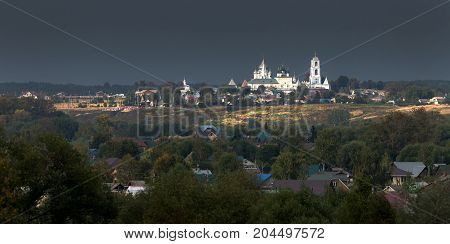 Nikitsky monastery in Pereslavl-Zalessky. Ancient Russian monastery. The temple is brightly lit by the low sun against a dark cloud. Yaroslavl region. Russia