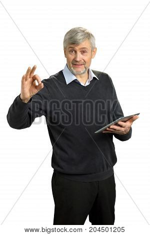Handsome mature man showing Ok sign. Cheerful senior man in formal wear gesturing OK sign with fingers and holding computer tablet on white background.