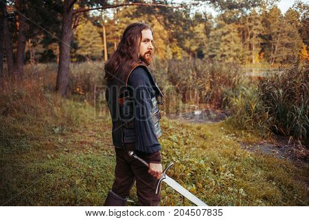 The bearded man knight. A guy in a medieval costume with a sword