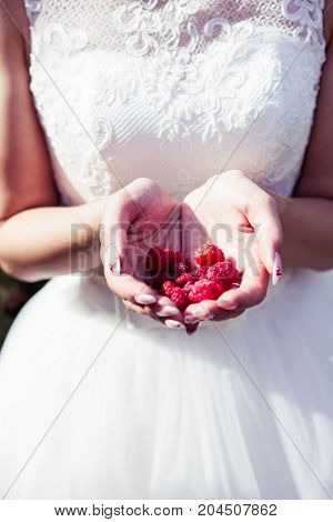 Girl bride holding raspberries in hands summer time joy