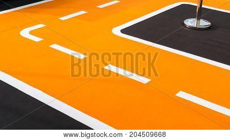 Curve of orange running track and lanes. Temporary setup detail on carpet floor.