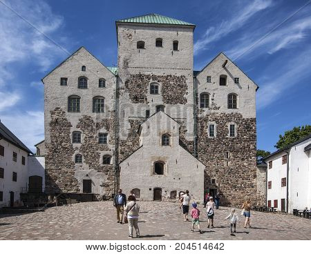 TURKU, FINLAND ON JUNE 30. Outdoor view of the Turku Medieval Castle from the 13th century on June 30, 2017 in Turku, Finland. Classical stone building. Unidentified people. Editorial use.