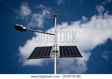 Lighthouse powered by solar energy against the blue sky. Top windmill with generator.