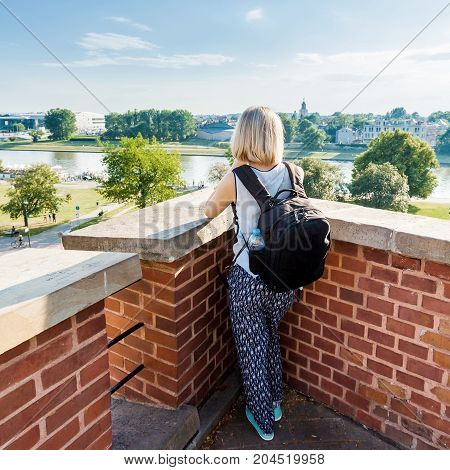 Female traveler stands and looking at modern residential quarter of Krakow and Vistula River. Wawel castle. Poland.
