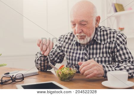 Senior man eating fresh salad side view. Mature male having healthy snack, healthcare, diet concept