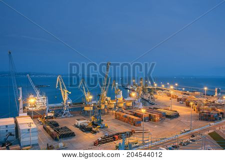 ALBANIA DURRES - September 22 2015: View of the cargo terminal in the evening. Unloading of the tanker by cargo cranes. A platform for storing sea freight containers. Cruise liners and cargo ships are moored in the port