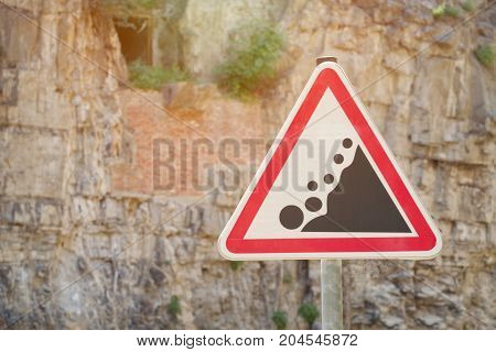 Road sign Caution rockfall against the background of a rock