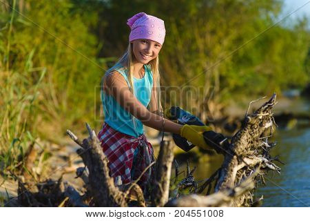 Teen girl with sabersaw is sawing a logs.