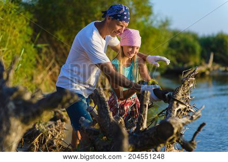 Father and Teen girl with sabersaw is sawing a logs.