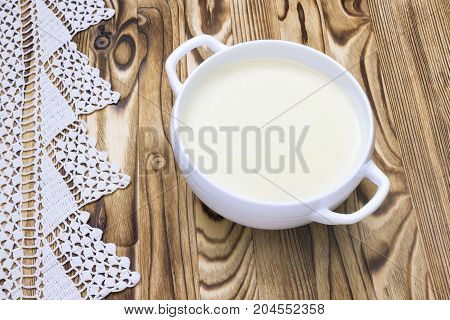 Tasty potato soup and handmade crochet napkin on rustic wooden table. Traditional lunch or dinner. Potato and onion vegan vegetarian healthy cream soup in white ceramic bowl