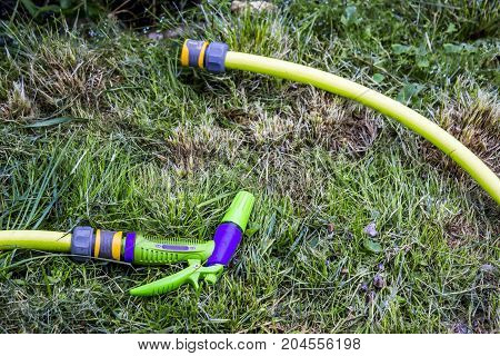 Flexible Hoses For Water In The Garden On The Grass. Nozzle - Sprinkler In The Form Of A Pistol, Con