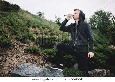 A young runner decided to have a short break after running a long distance and drink some water. He is really thursty.