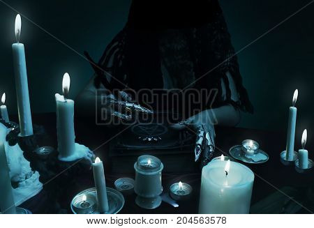 A sorceress holding a quill and magic book with pentagram symbol. Witchcraft composition, halloween concept, black magic ritual.