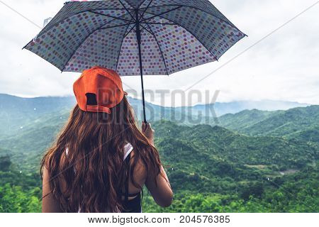 Asian women travel relax in the holiday. The women stood in rain umbrellas on the mountain. During the rainy season.Thailand
