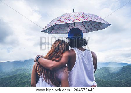 Lover women and men asians travel relax in the holiday. stood in rain umbrellas on the mountain. During the rainy season.Thailand