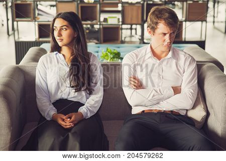 Resentful colleagues looking away from each other because of misunderstanding. Unhappy business people being quarreling and sitting on one sofa. Conflict concept