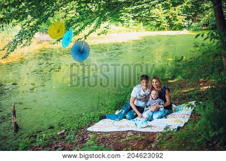 happy family walks in the park, sit on the bank of the lake and admire a decline