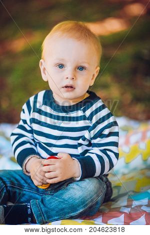 Cute child baby boy lying on blanket in summer day on nature. Happy smile, 1 year old, outdoor. Family picnic in a park.