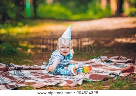 Little infant baby boy 1year kid on a plaid in park. Summer sunset. Copy space