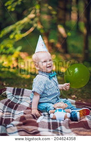Little infant baby boy 1year kid on a plaid in park. Summer sunset. Copy space