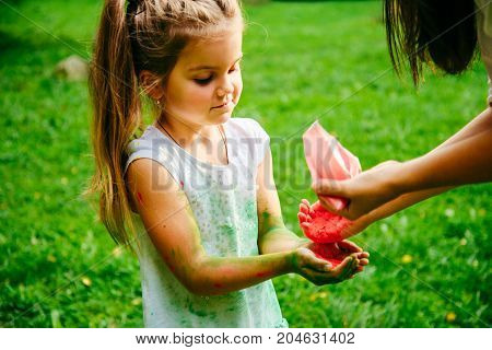 mother with daughter play with holi paints in city park