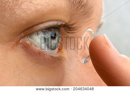 closeup of woman putting contact lens in her eye