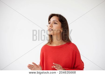 Pretty girl in red top having absorbed look and gesticulating as if listening to classic music. Brunette young female actress acting playing part looking inspired getting into her charactrer