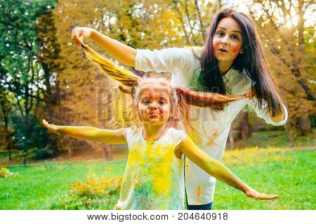 father mother and daughter full around with holi paints in city park
