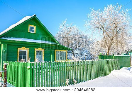 rural wooden house in winter covered with snow. a frost wintry day. green wooden home in village. rustic winter landscape