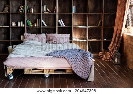 Modern bedroom in a loft. Urban apartment with pallet bed, scandinavian eco design