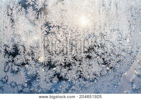 wintry frosty pattern on glass. abstract background of ice frozen window. winter day sun shine through frosted glass on window.