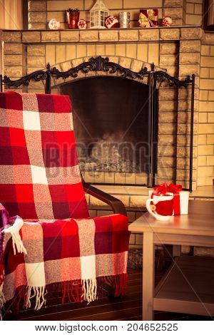Сheckered plaid on armchair near fireplace. Winter holiday concept