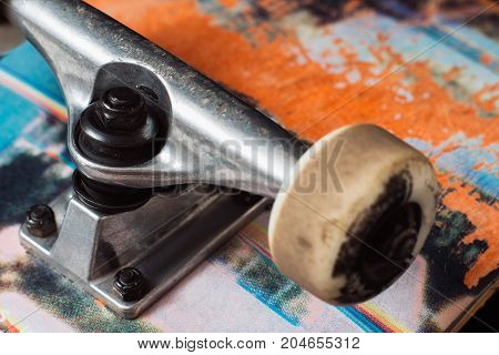 Skateboard truck with chassis close up, rubbed deck and wheels. Professional extreme sport and adjustment of skateboarding elements, safety construction kingpin, baseplate, hanger