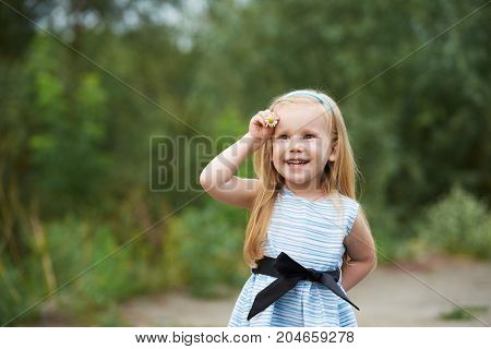 Young girl with flower. Blue dress. Smiling blond