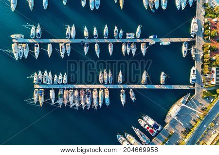 Aerial view of amazing boats at sunset in Marmaris, Turkey. Minimalistic landscape with boats and sea in marina bay. Top view from drone of harbor with yacht, motorboat and sailboat. Beautiful port