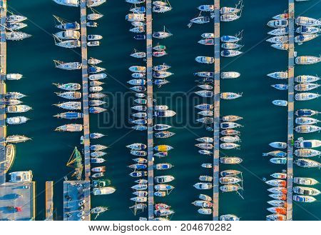 Aerial view of amazing boats at sunset in Marmaris, Turkey. Minimalistic landscape with boats and sea in marina bay. Top view from drone of harbor with yacht, motorboat and sailboat. Beautiful port