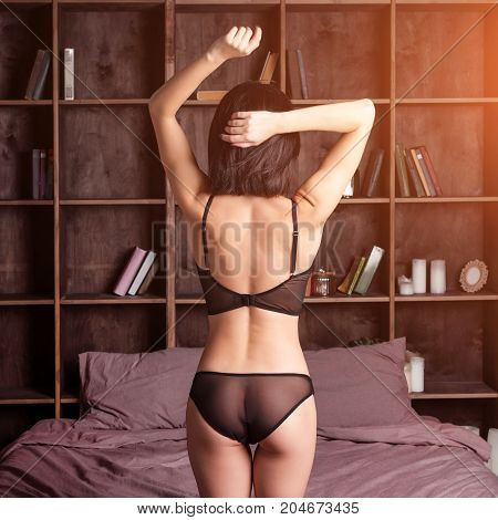 Seductive sexy gorgeous woman wearing lingerie in bed at home. Attractive sensual young girl. Female underwear fashion. Woman relaxing in bed in loft apartment