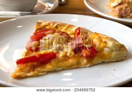Piece of pizza on white plate in caffeteria