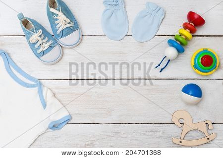 baby bodysuit and baby toys on wooden background. flat lay