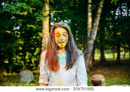 portrait of dark long hair woman all in holi paints in city park