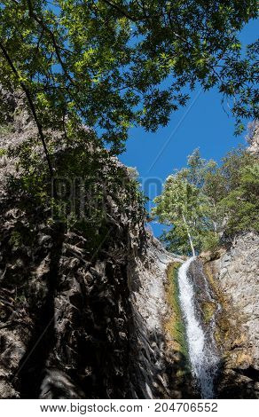 Beautiful small idyllic waterfall with water flowing through rocks. Millomery waterfall Troodos Cyprus.