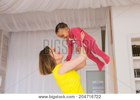 happy family. Mother throws up baby, playing at home.